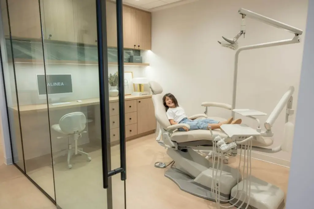 A smiling young patient in a treatment chair at Alinea Orthodontics